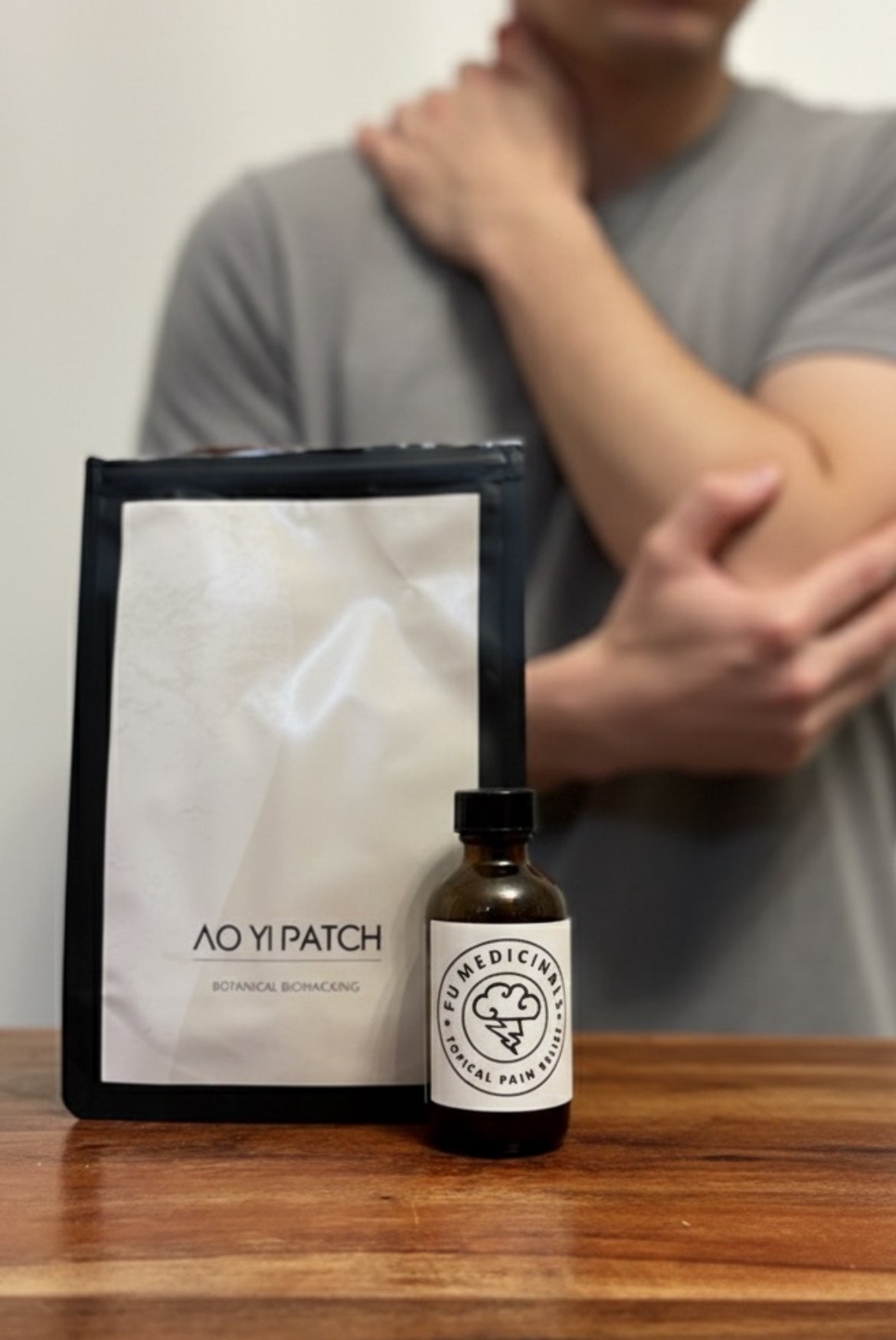 AO YI PATCH and a bottle of medicine on a wooden surface with a person in the background.