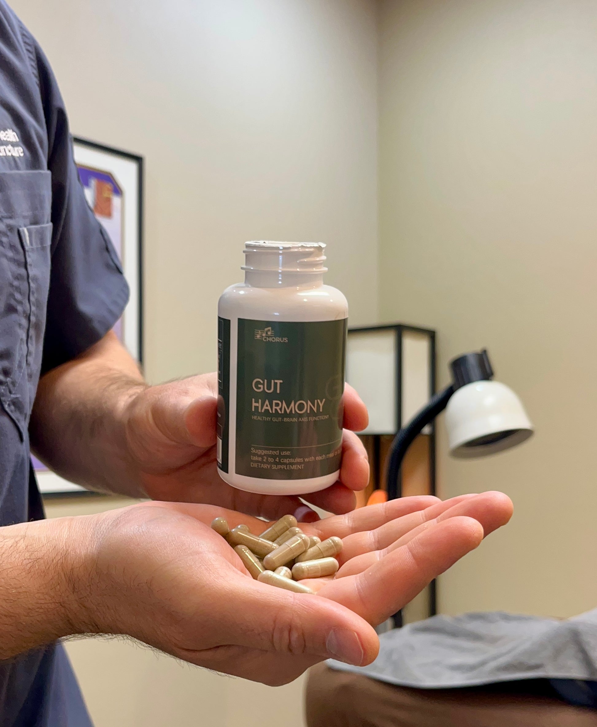 Person holding a bottle labeled 'Gut Harmony' with capsules in their hand.